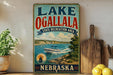 A vintage-style sign for Lake Ogallala, a state recreation area in Nebraska, featuring a boat on the water and a scenic landscape.