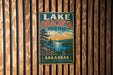A vintage metal sign for Lake Ouachita State Park in Arkansas, featuring a scenic landscape with pine trees, a lake, and mountains.