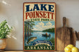 A vintage-style sign for Lake Poinsett State Park in Arkansas, featuring an illustration of a lake, trees, and a person fishing.