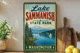 A vintage-style sign for Lake Sammish State Park in Washington, featuring a scenic landscape with a lake, mountains, and a sailboat.