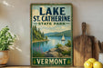 A vintage-style sign for Lake St. Catherine State Park in Vermont, featuring a scenic landscape with a lake, mountains, and a sailboat.