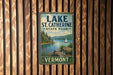 A vintage metal sign for Lake St. Catherine State Park in Vermont, featuring a scenic landscape with a lake, mountains, and a sailboat.