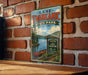 A vintage-style metal sign for Lake Tachkanic State Park in New York, featuring a scenic illustration of a lake, trees, and a canoe.