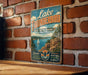 A vintage-style sign for Lake Thunderbird State Park in Oklahoma, featuring a scenic illustration of a lake, mountains, and a sailboat.