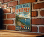A vintage-style metal sign for Lake Whitney State Park in Texas, featuring a scenic landscape with a lake, mountains, and a sailboat.