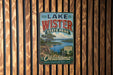A vintage metal sign for Lake Wister State Park in Oklahoma, featuring a scenic landscape with a lake and mountains.