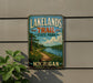 A vintage-style metal sign for Lakelands Trail State Park in Michigan, featuring a scenic landscape with a path leading through a forest and a lake.
