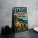 A vintage metal sign for Lakeside Beach State Park in New York, featuring a beach scene with a lifeguard tower, chairs, and a sailboat.
