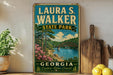 A vintage-style sign for Laura S. Walker State Park in Georgia, featuring a scenic landscape with a bridge and trees.