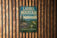 A vintage metal sign for Laurel Mountain State Park in Pennsylvania, featuring a scenic landscape with mountains, trees, and flowers.