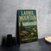 A vintage-style metal sign for Laurel Mountain State Park in Pennsylvania, featuring a scenic landscape with mountains, pine trees, and flowers.