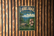 A vintage-style metal sign for Laurel Ridge State Park in Pennsylvania, featuring a scenic landscape with mountains, trees, and flowers.