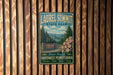 A vintage-style metal sign for Laurel Summit State Park, featuring a scenic mountain landscape with pine trees and pink flowers.