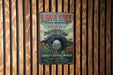A vintage-style metal sign for the Lava Tree State Monument in Hawaii, featuring a tree with a hole in its trunk and a scenic landscape.