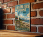 A vintage-style metal sign for Leadbetter Point State Park in Washington, featuring a lighthouse and a coastal landscape.