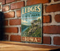 A vintage-style metal sign for LEDGES STATE PARK in Iowa, featuring a scenic landscape with a river and rocky cliffs.