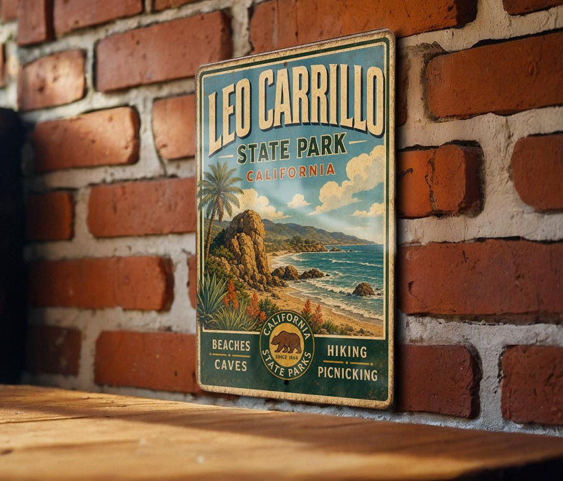 A vintage-style metal sign for Leo Carrillo State Park in California, featuring a beach, palm trees, and a mountain landscape.