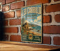 A vintage-style metal sign for Leo Carrillo State Park in California, featuring a beach, palm trees, and a mountain landscape.
