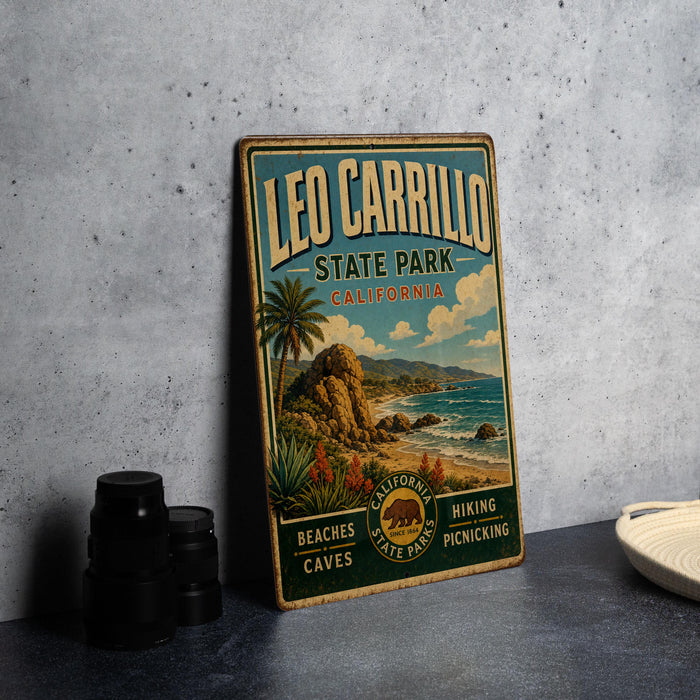 A vintage-style metal sign for Leo Carrillo State Park in California, featuring a beach scene with palm trees and mountains.