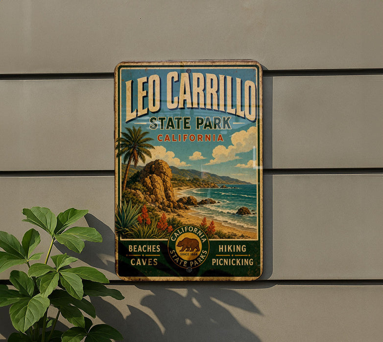 A vintage-style metal sign for Leo Carrillo State Park in California, featuring a scenic landscape with palm trees, mountains, and a beach.