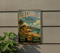 A vintage-style metal sign for Leo Carrillo State Park in California, featuring a scenic landscape with palm trees, mountains, and a beach.