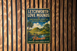 A vintage-style metal sign for Lechworth-Love Mounds, an archaeological state park in Florida, featuring a landscape with palm trees and hills.
