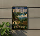 A vintage-style metal sign for Levi Jackson Wilderness Road, State Park, Kentucky, featuring a scenic landscape with a cabin and trail.
