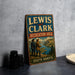 A vintage metal sign for the Lewis and Clark Recreation Area in South Dakota, featuring a scenic landscape with two figures in the foreground.