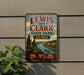 A vintage-style sign for Lewis and Clark State Park in Iowa, featuring a scenic landscape with a river, mountains, and two figures in period clothing.