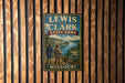 A vintage metal sign for Lewis and Clark State Park in Missouri, featuring a scenic illustration of the Missouri River and two figures in historical attire.
