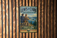A vintage-style metal sign for the Lewis and Clark State Recreation Site in Oregon, featuring two hikers on a trail overlooking a scenic landscape.