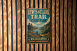 A vintage metal sign for Lewis & Clark Trail State Park, featuring a scenic illustration of a mountain landscape with a canoe, is displayed on a wooden wall.