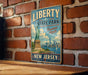 A vintage-style metal sign with the text "LIBERTY STATE PARK" and "FREEDOM AWAITS" hangs on a brick wall.