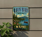A vintage-style metal sign for "Lily Bay State Park" in Maine, featuring a scenic landscape with a lake, mountains, and a canoe.