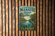 A vintage metal sign for Little Manatee River State Park in Florida, featuring a scenic illustration of the river and surrounding landscape.