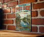 A vintage-style metal sign for Little Pee Dee State Park in South Carolina, featuring a scenic illustration of a lake and surrounding nature.