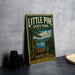 A vintage-style metal sign for Little Pine State Park in Pennsylvania, featuring a scenic landscape with pine trees, a lake, and mountains.