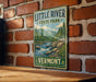 A vintage-style metal sign for Little River State Park in Vermont, featuring a scenic illustration of a river and mountains.