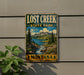 A vintage-style metal sign for Lost Creek State Park in Montana, featuring a scenic landscape with mountains, forests, and a river.