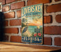 A vintage-style sign for "Lovers Key State Park" in Florida, featuring a beach scene with a crane, palm trees, and a sunset.