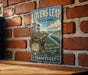 A vintage-style metal sign for "Lovers Leap State Park" hanging on a brick wall, featuring a scenic landscape with a river and mountains.