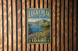 A vintage metal sign for Lucky Peak State Park in Idaho, featuring a scenic mountain landscape with a lake and wildflowers.