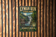 A vintage-style metal sign for Lyman Run State Park in Pennsylvania, featuring a scenic image of a waterfall surrounded by trees.