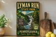 A vintage-style sign for Lyman Run State Park in Pennsylvania, featuring a scenic waterfall and lush greenery.