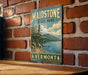 A vintage-style metal sign for Maidstone State Park in Vermont, featuring a scenic landscape with mountains, trees, and a lake.
