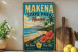 A vintage-style sign for Makena State Park in Hawaii, featuring a tropical beach scene with palm trees, flowers, and a mountain in the background.
