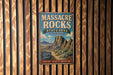 A vintage metal sign for Massacre Rocks State Park in Idaho, featuring a desert landscape with mountains in the background.