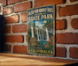 A vintage-style metal sign for McCarthy-Burney Falls Memorial State Park in Northern California, featuring a waterfall and lush greenery.