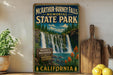 A vintage-style sign for "McArthur-Burney Falls Memorial State Park" in California, featuring a waterfall surrounded by trees and flowers.