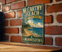 A vintage-style metal sign for McCarthy Beach State Park in Minnesota, featuring a scenic beach landscape with pine trees and a lake.